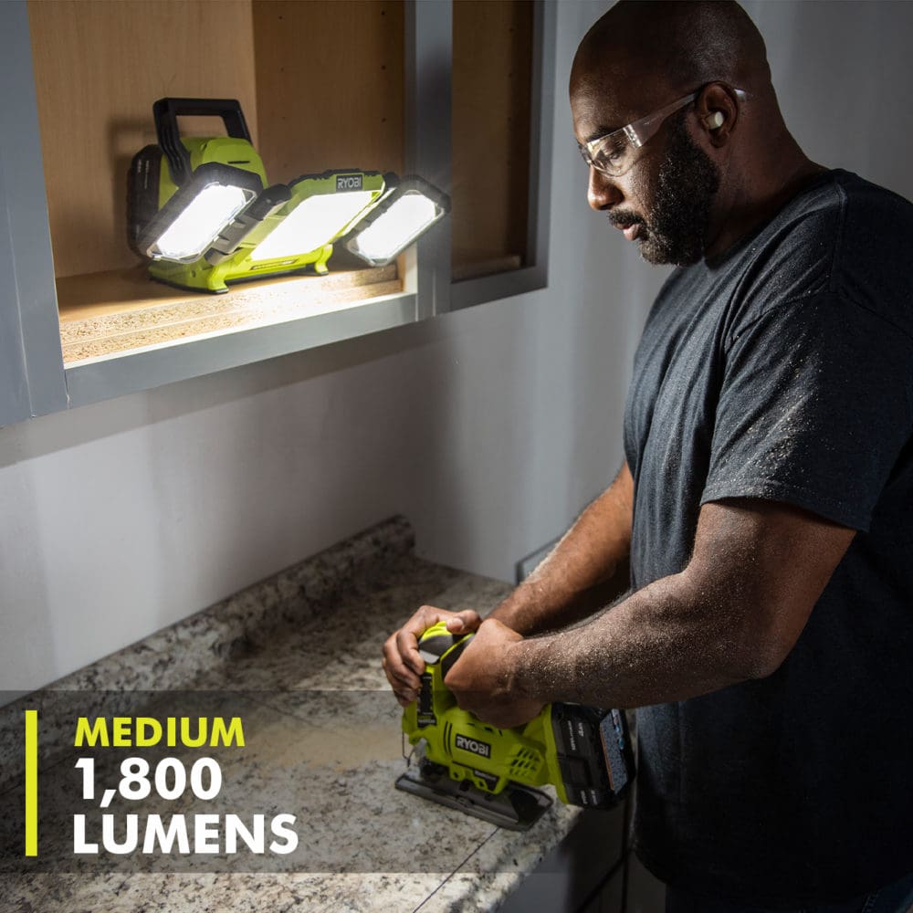 Image of a man using a jig saw in a dark space that is being lit by a battery-powered light. The words "Medium 1,800 Lumens" are on the image, as an example of rich content for Home Depot's website